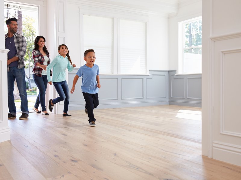 young family entering empty house with new floors